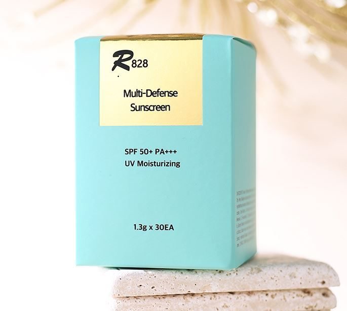 R828 Multi-Defense Sunscreen SPF 50+ PA+++ box on sand
